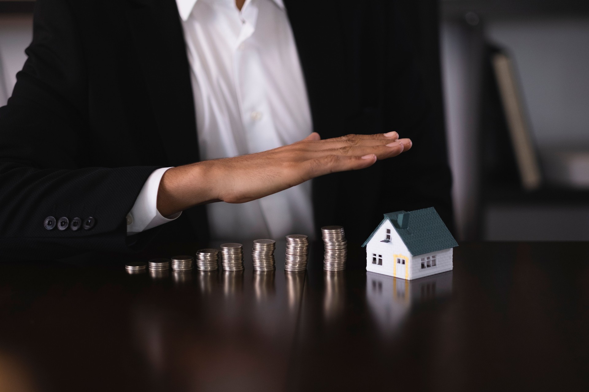 Businesswoman protecting increasing stack of coins and house model